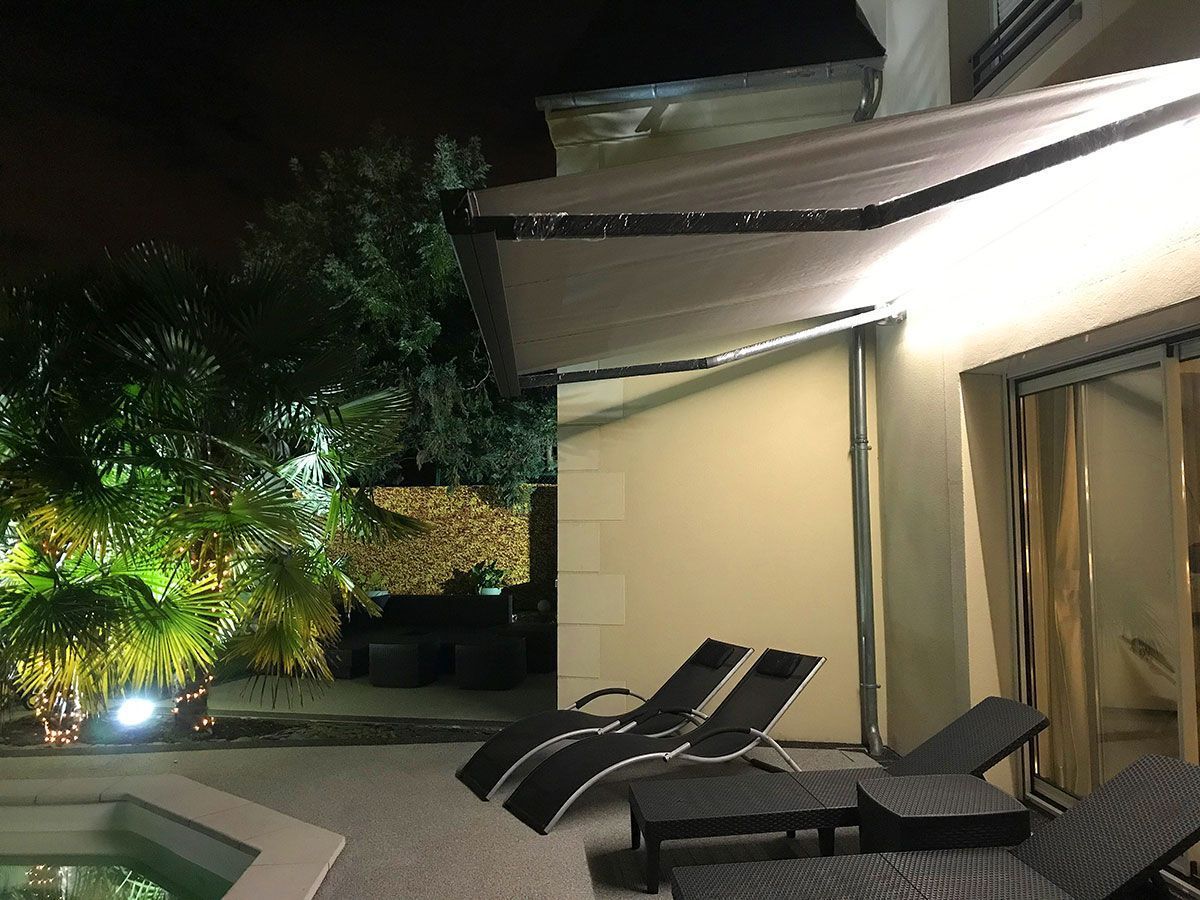 Store banne avec option LED au bord de la piscine